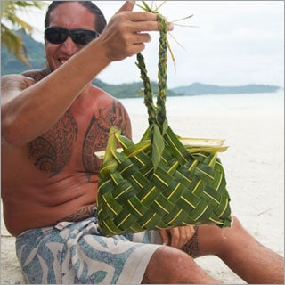 Native Polynesian male presenting a hand-woven palm leave basket.