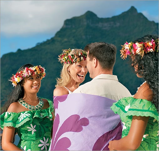 Two cruise guests enjoying a wedding ceremony wrapped in a Taifaifai.