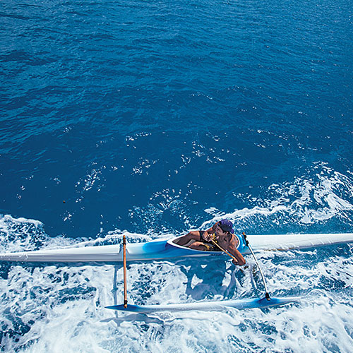 A native Polynesian man operating an ocean canoe.