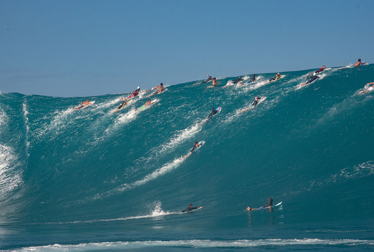 Paul Gauguin Cruises | Surfers lined up on an ascending wave