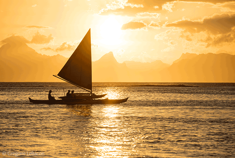 Polynesian boat sails at sunset