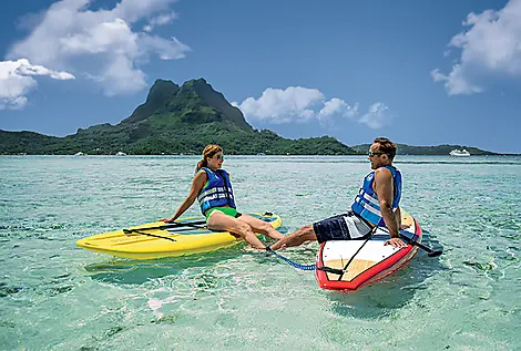 Paul Gauguin Cruises | Couple on paddleboards in Society Islands