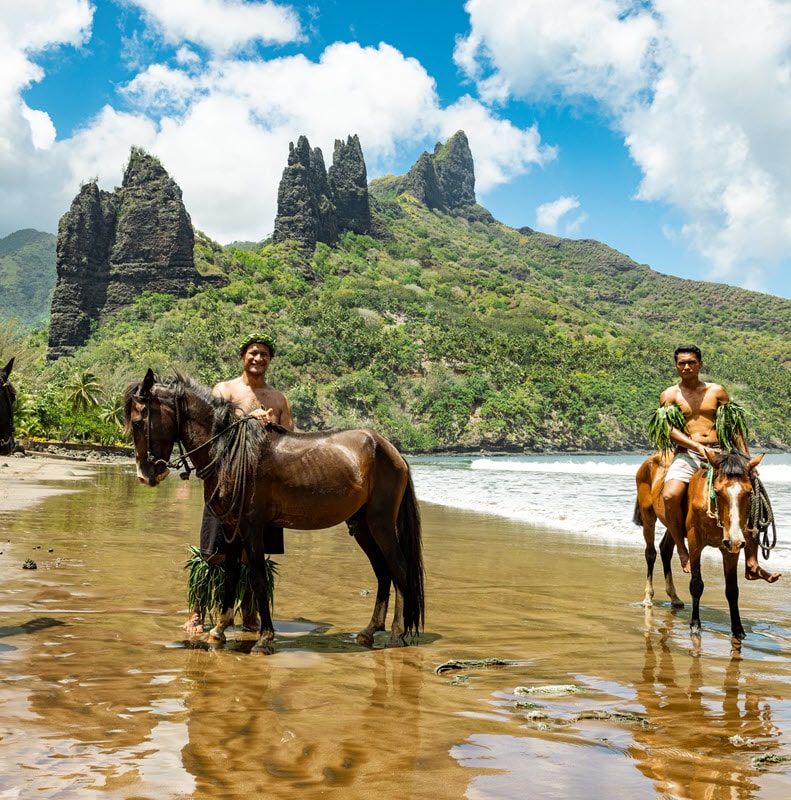 Paul Gauguin Cruises | Locals on horseback in beach
