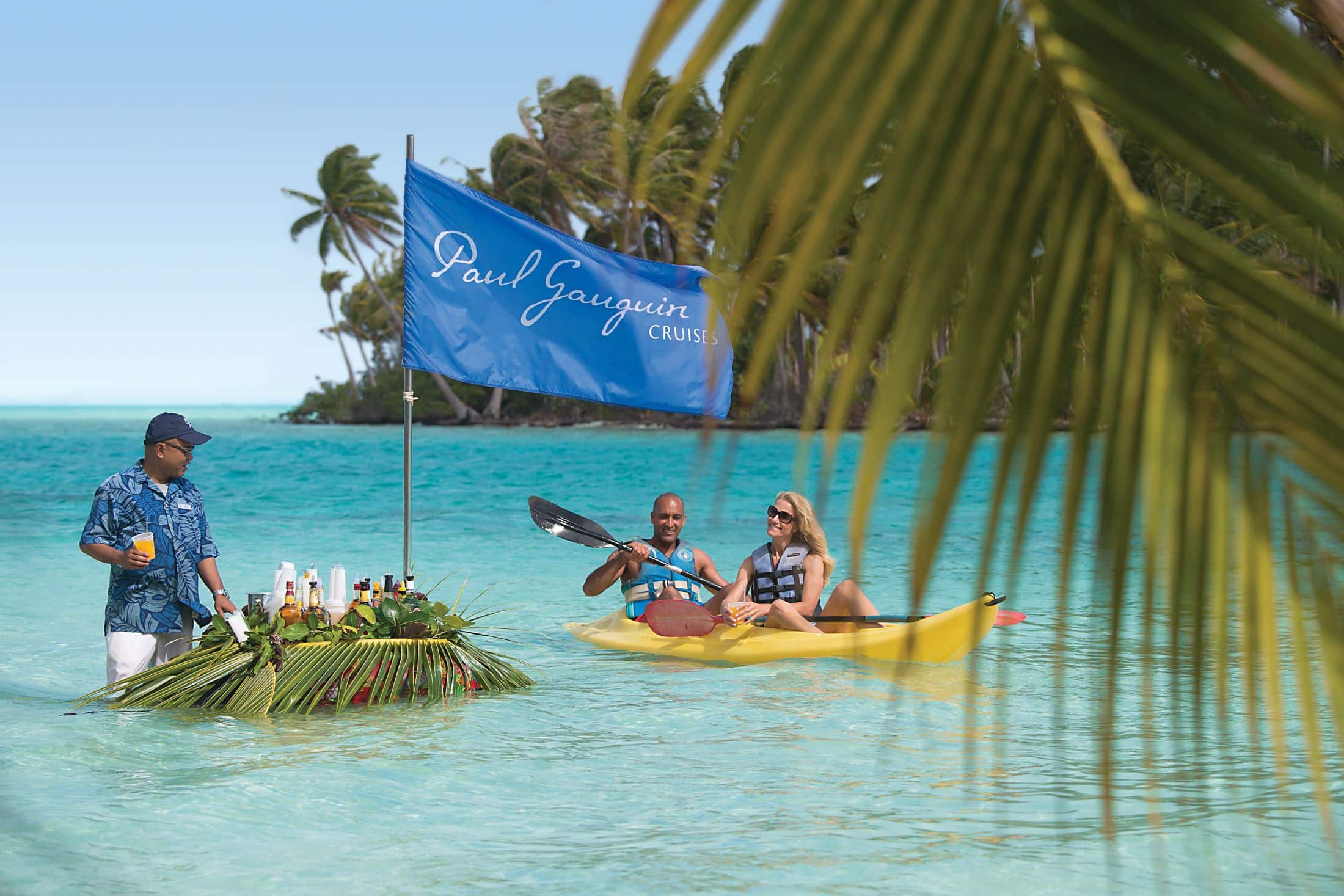 Couple kayaking in Motu Mahana toward the Paul Gauguin Cruises floating bar 